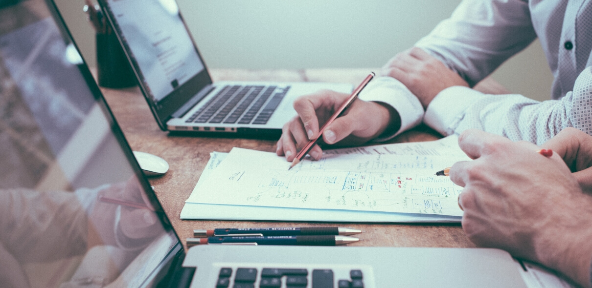 Two people mark through paperwork as they discuss AGF church insurance programs